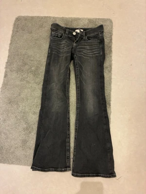 Svarta bootcut jeans med brodyr - Säljer ett par svarta bootcut jeans med snygg slitning och vita broderade detaljer på bakfickorna. Jeansen har låg midja, klassisk femficksmodell och kontrastsömmar. Perfekta för dig som gillar en unik och trendig look.bara att skriva till mig om ni skulle vilja ha med bilder och liknande🤍