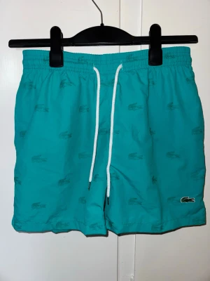 Lacoste badbyxor - Fraktar inom 24h✅Helt oanvända Lacoste badbyxor i storlek L/jr, passar Xxs-Xs