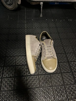 Lanvin - Snygga beige sneakers med lågt skaft, ovandel i mocka och tåparti i slätt läder. Skorna har vita sulor och matchande beige skosnören. Perfekta för en clean och stilren look.