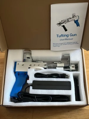 Elektrisk tufting gun för mattor - Säljer en elektrisk tufting gun med blått handtag och metallkropp, perfekt för att skapa egna mattor och textilkonst. Medföljer strömadapter, sladd och användarmanual. Verktyget är robust och har en modern design med detaljer i plast och metall.