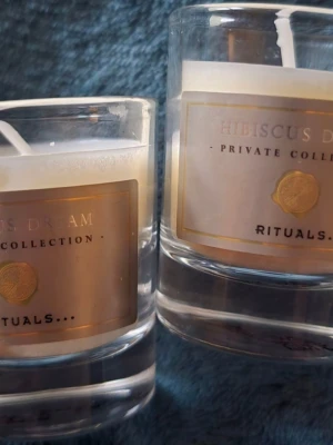  2 st Doftljus Hibiscus Dream från Rituals - Två exklusiva doftljus från Rituals Private Collection i doften Hibiscus Dream. Ljuset kommer i genomskinliga glasbehållare med guldfärgade etiketter och vita vaxljus. Perfekt för att skapa en mysig atmosfär hemma.