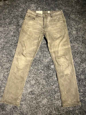 Led noble jeans grå - Snygga beige jeans med rak passform och klassisk femficksdesign. Jeansen har bälteshällor och guldfärgade nitar vid fickorna. Materialet ser ut att vara bomullsdenim med en något tvättad look. Perfekta för en avslappnad och trendig stil. 30/32