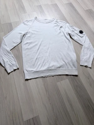 Vit C.P. Company sweatshirt - Säljer den här riktigt feta C.P. Company tröjan som är i riktigt bra skick, tröjan sitter riktigt snyggt och är perfekt vit färg nu till sommaren! Tröjan är i storlek S. Hör av er vid minsta fundering!!