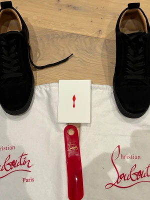 Christian Louboutin Louis Spikes sneakers - Snygga Louis Spikes Orlato Flat sneakers från Christian Louboutin i svart mocka med klassiska svarta skosnören. Märkets ikoniska röda detaljer och exklusiv design. Skorna har låg profil och är perfekta för dig som gillar lyxiga statement-plagg. Pris kan diskuteras!