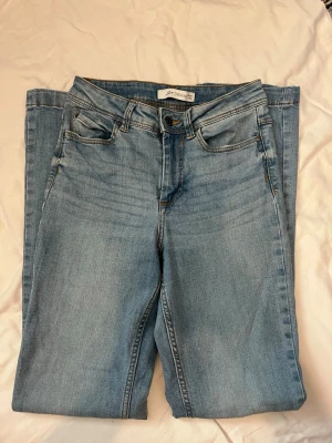 Ljusblå raka jeans från Jdy demin  - Säljer ett par ljusblå jeans från Jdy Denim med klassisk femficksmodell med utsvängda ben. Jeansen har normal midja, bälteshällor.