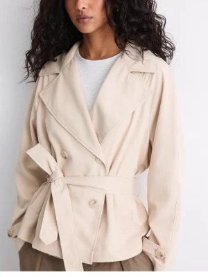 Beige trenchcoat med knytskärp - Stilren beige trenchcoat med dubbelknäppning och brett slag. Jackan har ett avtagbart knytskärp i midjan och dekorativa knappar vid ärmsluten. Tillverkad i ett mjukt tyg som ger en avslappnad men ändå chic look.