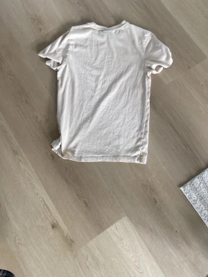 Vit basic t-shirt i bomull - En enkel vit t-shirt med rund hals och korta ärmar. Tillverkad i mjuk bomull, perfekt för en clean och avslappnad stil. Passar till det mesta och är ett måste i garderoben.