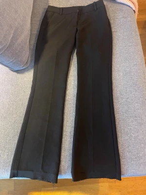 Svarta utsvängda kostymbyxor - Snygga svarta kostymbyxor med utsvängda ben och rå kant nertill. Byxorna har pressveck framtill. Byxorna är uppsprättade längst ner. Använd få gånger (pris kan diskuteras☺️)