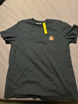 Moncler t-shirt - Säljer en t-shirt från Moncler med klassisk rund hals och korta ärmar. Köptes sommaren 2024 och har bara använts när jag provat den. Inget kvitto