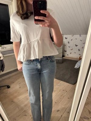 Vit volang topp i bomull - Söt vit topp med volang nedtill och korta ärmar i bomull. Har varit en favorit tröja🥹💞