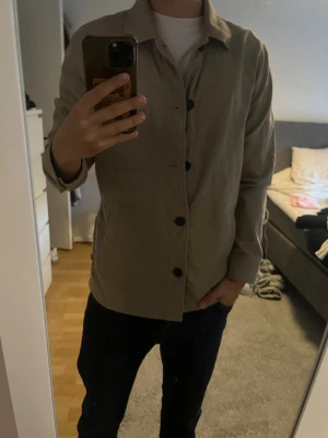Beige overshirt från Matinique - Stilren beige overshirt från Matinique med klassisk krage och stora knappar framtill. Denna är använd Max 2 gånger 