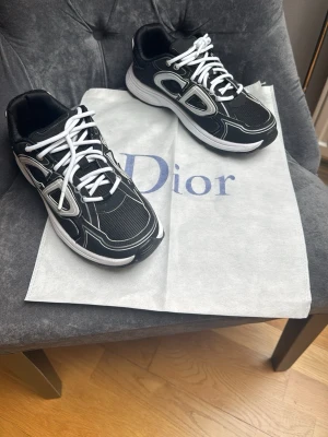 Svarta vita skor  - Snygga svarta märkes sneakers med vita och silverfärgade detaljer samt vita snören. Perfekt nu till sommaren om du vill sticka ut med ett par feta skor. Använda 1 gång o aldrig mera. Storlek 41 men passar även 42 