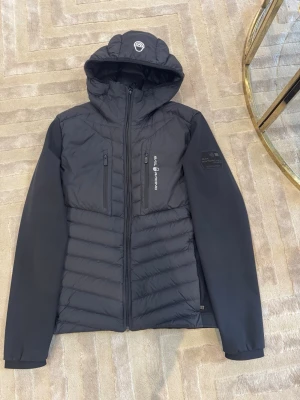 Sail Racing dunjacka – 800 FP – svart – storlek S - Säljer en snygg och funktionell dunjacka från Sail Racing i storlek S. Jackan är i mycket fint skick och sparsamt använd.  🔹 800 fill power dun (väldigt varm och lätt) 🔹 Vind- och vattenavvisande 🔹 Stretchpaneler i ärmar för bättre rörelsefrihet 🔹 Huva och flera praktiska fickor 🔹 Stilren svart färg – passar till allt  Perfekt som höst-/vinterjacka eller för kalla vårdagar.  Nypris ca 4 000–6 000 kr.  💰 Pris: 1 650 kr  Finns att hämta i Stockholm eller skickas mot fraktkostnad. 