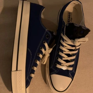 Low Top Converse - ”Chrome Hearts” Customs - 🔷 Blue canvas low-top sneakers combining the classic Converse silhouette with Chrome Hearts detailing  🔷 Durable canvas upper in a deep blue tone that gives the shoe a clean yet bold look  🔷 Iconic Converse high-top design inspired by the timeless Chuck Taylor sneaker heritage  🔷 Premium metal details that add a distinctive luxury streetwear touch  🔷 White rubber toe caps and vulcanized sole creating a strong contrast with the blue canvas  OBS: NOT CHROME HEARTS, JUST INSPIRED