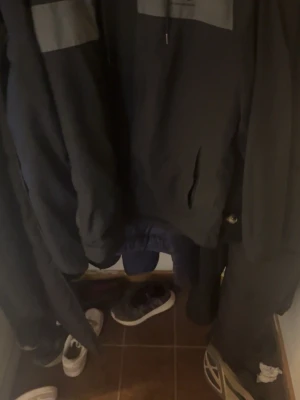 Svart under armour vindjacka  - Säljer en svart under armour jacka  med huva och dragsko. Jackan  har en enkel design med fickor på sidorna och en diskret detalj i form av en ljusare panel upptill. Perfekt för en avslappnad och stilren look. Storlek S men passar den som tar M lika bra priset är ej fast. skickar samma dag 