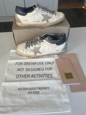 Golden Goose mörkblå tail - Säljer ett par golden goose med mörkblå tail i storlek 44. Skick ses i bilderna de är ganska använda och sulan har lossat lite där bak men det går såklart att limma om man har något starkt lim. Hör av vid minsta fråga Priset går att diskutera 