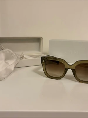 Chimi solglasögon - Snygga solglasögon från CHIMI i modell X14, i princip 08, med transparent gröna bågar och bruna tonade glas. Rektangulär form som ger en cool och modern vibe. Perfekt accessoar för att lyfta din stil.