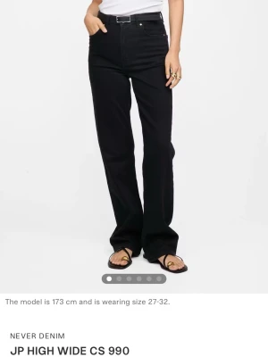 Helt nya! Svarta straight jeans, W28 L32 - Säljer ett par svarta high waist jeans från Never Denim, modell JP High Wide CS 990. Jeansen har raka, vida ben och klassisk femficksdesign. Tillverkade i denim med en snygg svart tvätt och knappgylf. Perfekta för en avslappnad och trendig look. Nypris 599kr 