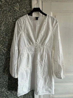 Vit långärmad klänning  - Kort vit långärmad klänning från lindex. Klänningen har broderade blommor över hela tyget. Perfekt för sommaren och studenten!🌸