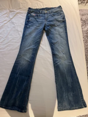 Blå low waist bootcut jeans från Diesel - Skitsnygga blå low waist bootcut jeans från Diesel. Passar inte mig därför jag säljer, helt oanvända och nyskick. Midjemåttet rakt över är 35 cm och innerbenslängden är 82 cm🩵