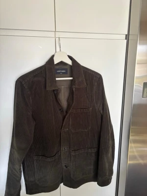 Brun manchester overshirt A Day's March - Snygg grön overshirt i manchester från A Day's March. Klassisk rak passform med tre fickor framtill och knäppning med svarta knappar. Perfekt lager-på-lager-plagg med stilren krage och diskret bröstficka.