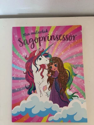 Min målarbok Sagoprinsessor - Färgglad målarbok med sagotema där prinsessor och enhörningar står i fokus. Omslaget har starka rosa, lila och regnbågsfärger med glittereffekt. Boken har 96 sidor fyllda med prinsessmotiv att färglägga. Det finns 2 sidor i boken som är målat lite i (se bilder) annars är den i mycket fint skick.