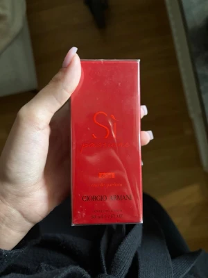 Giorgio Armani Sì Passione EdP 50ml - Giorgio Armani Sì Passione Eau de Parfum i en snygg röd rektangulär förpackning. Doften är elegant och feminin, perfekt för dig som gillar fruktiga och blommiga toner. Flaskan är tillverkad av glas och kommer i en lyxig kartong.