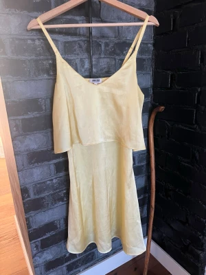 Ljusgul omlottklänning  - Säljer en ljusgul omlottklänning från Bubbelroom storlek 36 men passar även mig som 38. smala axelband och v-ringad hals. Klänningen har ett lager över bysten och är tillverkad i ett lätt, glansigt material som ger en somrig känsla. Perfekt för varma dagar och har en flowy passform.