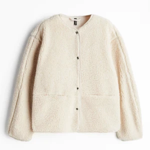 Beige teddyjacka  - Mysig beige teddyjacka i fluffigt pilematerial. Jackan har rund halsringning, tryckknappar framtill och två stora fickor. Perfekt för dig som vill ha en enkel och stilren look med maximal komfort. Aldrig använd! Nytt skick! Slutsåld överallt! (Sorry för dåligt ljus i andra bilden)