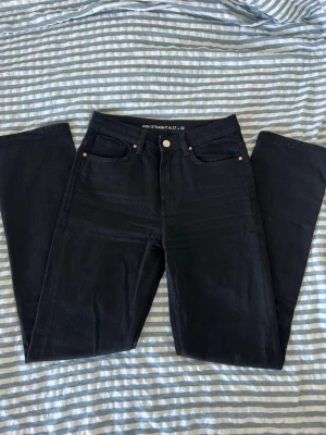 Svarta high straight jeans - Säljer ett par svarta high straight jeans med klassisk femficksdesign och raka ben. Jeansen har hög midja och knappgylf. Perfekta för en clean och stilren look. Materialet är troligtvis bomull med lite stretch för extra komfort.