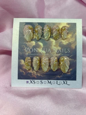 GoldenDrip (XS);Short Almond - Handgjorda press-on naglar i storlek XS: 14 mm, 11 mm, 11,5 mm, 10 mm, 8 mm . Naglarna har en mjuk nude och  skimrande finish och detaljerade guldfärgade mönster. Formen är short almond och perfekta för dig som vill ha unika och lyxiga naglar.