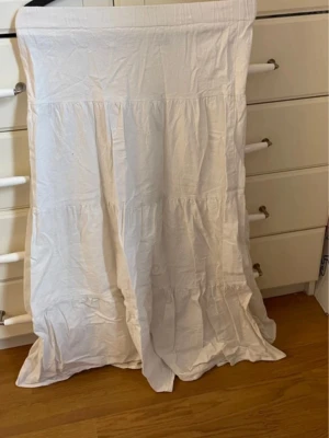 Vit långklänning från SHEIN - Luftig vit långklänning från SHEIN i storlek XS. Klänningen har en enkel, rak passform med flera volangdetaljer längs kjolen. Perfekt för sommarens varma dagar och har en mjuk känsla mot huden.