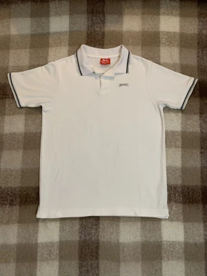 3st för 75  - Två klassiska pikétröjor från Slazenger, en i vitt och en i blått. Båda har krage med smala kontrastlinjer, korta ärmar och liten logga på bröstet. Perfekt till jeans eller shorts för en sportig och stilren look.