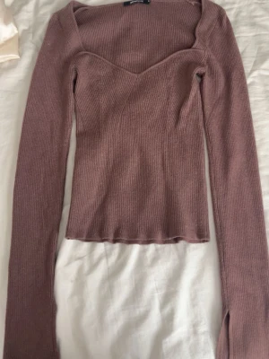 Ljusbrun ribbad långärmad topp - Trendig ljusbrun ribbad topp med lång ärm och v-ringad halsringning. Figurnära passform och mjukt stretchigt material som känns skönt mot huden. Perfekt till jeans eller kjol för en snygg look.