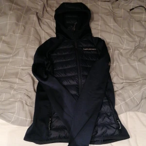 Svart hybrid Peak Performance jacka - Snygg svart jacka från Peak Performance med huva och hybrid framsida och rygg pris kan diskuteras 