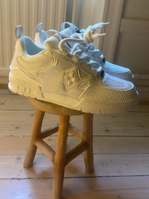 Vita Louis Vuitton sneakers - Snygga helvita sneakers från Louis Vuitton med mesh och läderdetaljer. Skorna har tydliga LV-loggor, grova snören och en chunky sula. Perfekta för dig som gillar exklusiv streetwear och vill sticka ut med en unik design. Kan shippa eller mötas upp 📍Vasastan.  Passar 43-44 priset är inte hugget i sten