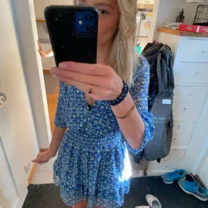 Blå mönstrad kortklänning med v-ringning - Supersöt blå kortklänning med vitt mönster och v-ringning. Klänningen är långärmad men på denna bild har jag vikt upp den. piss snygg och kan användas när som.  jätte bra skick då den är använd max 3-4 gånger! skriv för fler frågor 