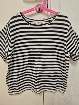 Randig t-shirt från 157, XS - Snygg svartvit randig t-shirt från 157 i storlek XS. Klassisk modell med rund hals och korta ärmar. Perfekt till jeans eller kjoj.