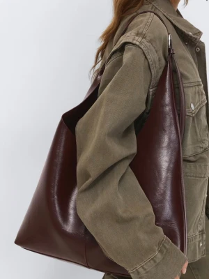 Vinröd shoppingväska  - Stilren och rymlig shoppingväska i vinröd färg med mjuk, slät finish. Väskan har en enkel, triangulär form och långa axelband som gör den lätt att bära över axeln. Perfekt för dig som vill ha en trendig och praktisk accessoar.