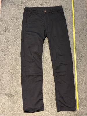 Svarta chinos  - Säljer ett par svarta chinos från RVLT med klassisk rak passform. Byxorna har två sidofickor fram, två bakfickor och bälteshällor. Stängs med knapp och dragkedja. Perfekta för en clean och stilren look. Dom är i ny skick och ser knappast ut. Priset är ej hugget i sten 
