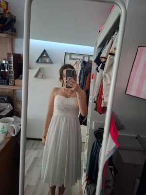 Vit spetsklänning utan axelband - Säljer en söt vit klänning utan axelband och vacker spets upptill. Klänningen har en markerad midja och ett lätt, flödande tyg som ger en romantisk känsla. Perfekt för sommarens varma dagar och speciella tillfällen. Aldrig använd.