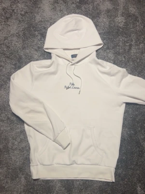 Vit hoodie från Polo Ralph Lauren - Snygg vit hoodie från Polo Ralph Lauren med broderad logga på bröstet. Klassisk känguruficka framtill, justerbar huva med dragsko och ribbade muddar. Tillverkad i mjukt bomullsmaterial för skön känsla.