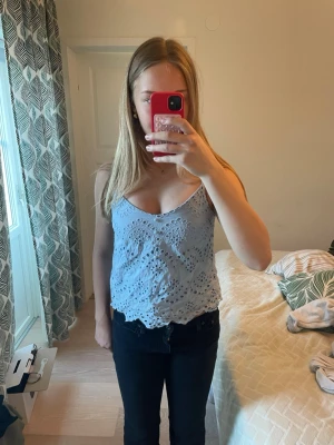 Ljusblå spetslinnetopp från Pieces - Säljer en ljusblå linnetopp från Pieces med tunna axelband och vacker spetsdetalj. Toppen har ett vågigt mönster med broderade hål och scallop-kant nertill. Perfekt för sommarens alla tillfällen, superenkel att matcha med jeans eller kjol🌺