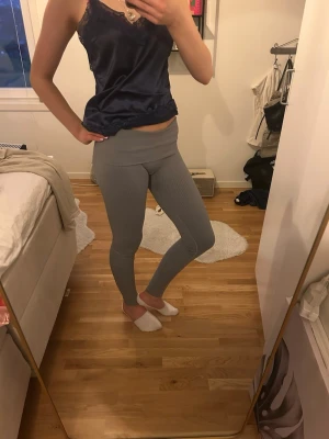 Grå ribbade leggings med hög midja - Säljer ett par grå leggings med ribbad struktur och hög midja men går att vika ner. De är stretchiga och sitter tight, perfekta för en avslappnad och trendig look. Materialet känns mjukt och följsamt mot huden. Passar perfekt till både oversized tröjor och crop tops.💞