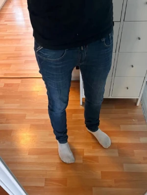 Replay Anbass - Säljer ett par blå Replay anbass jeans med klassisk femficksdesign och snygga sömmar på bakfickorna. Jeansen har passformen slim och är tillverkade i denim. Perfekta för dig som gillar en stilren look. Modellen är 185