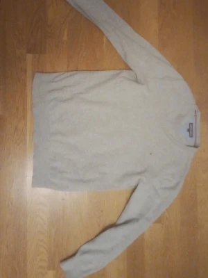 Ljusgrå tröja från Tommy Hilfiger - En stilren ljusgrå tröja från Tommy Hilfiger med diskret logga på bröstet. Tröjan har rund halsringning och långa ärmar. Perfekt för en enkel och klassisk look.