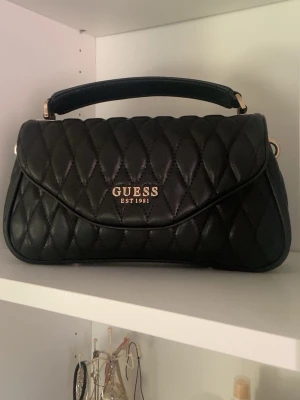 Guess handväska - Jättefin svart guess handväska, som kommer med skärp!💕 Har använts några gånger men är i rätt så bra skick.
