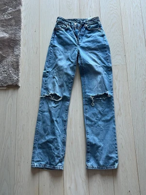 Blå ripped wide jeans  - Säljer ett par blå regular wide jeans med hål vid knäna. Waste 26  längd 32 tror dom är från BikBok 
