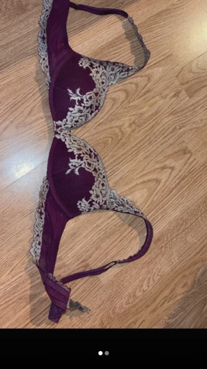 Intimissmi bh  - Snygg vinröd bh med beige spetsdetaljer längs kuporna och banden. Bh:n har vadderade kupor och justerbara axelband. Perfekt för dig som gillar en feminin och elegant stil.