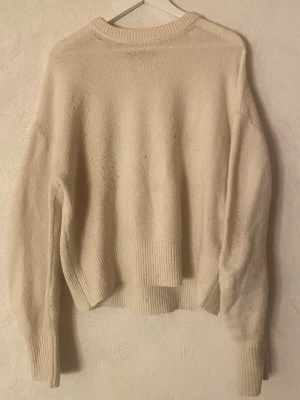 Cremevit stickad tröja - Mysig cremevit stickad tröja från BikBok i storlek M. Tröjan har en avslappnad passform, ribbade muddar vid ärmslut och nederkant samt rund halsringning. Perfekt för lager på lager under kyliga dagar.